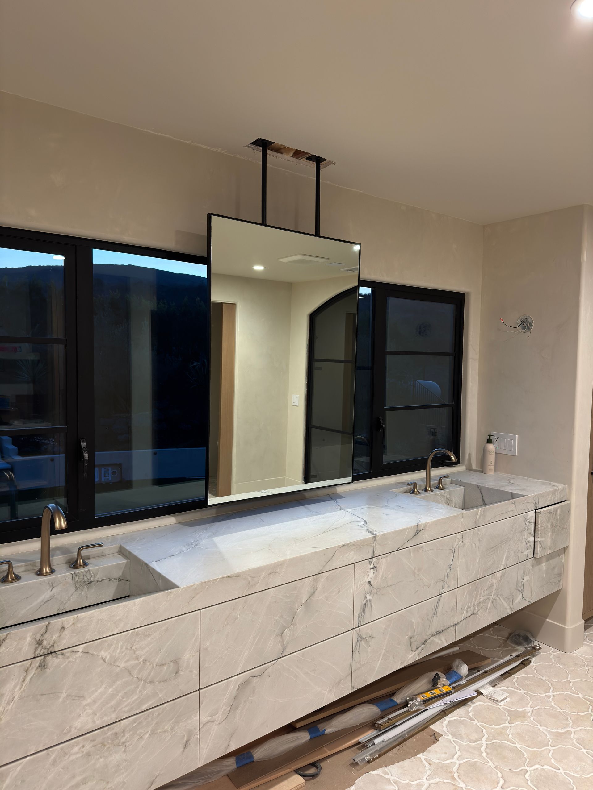 A bathroom with two sinks and a large mirror hanging from the ceiling.