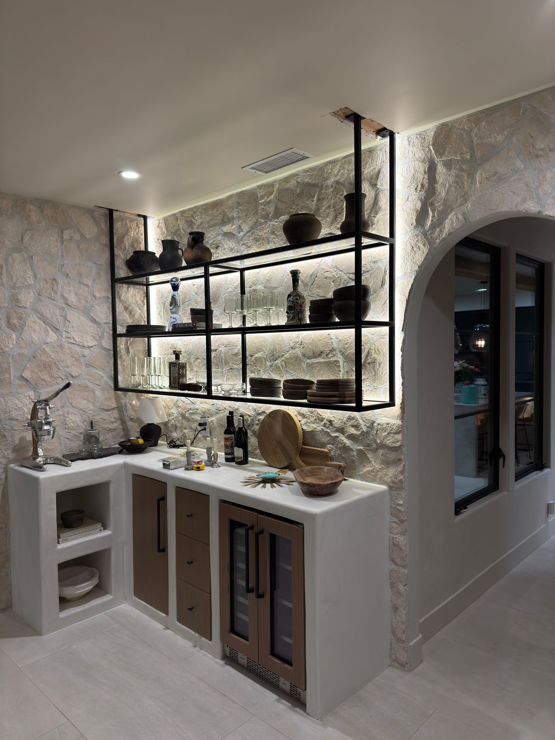 A kitchen with a sink , shelves , and a refrigerator.