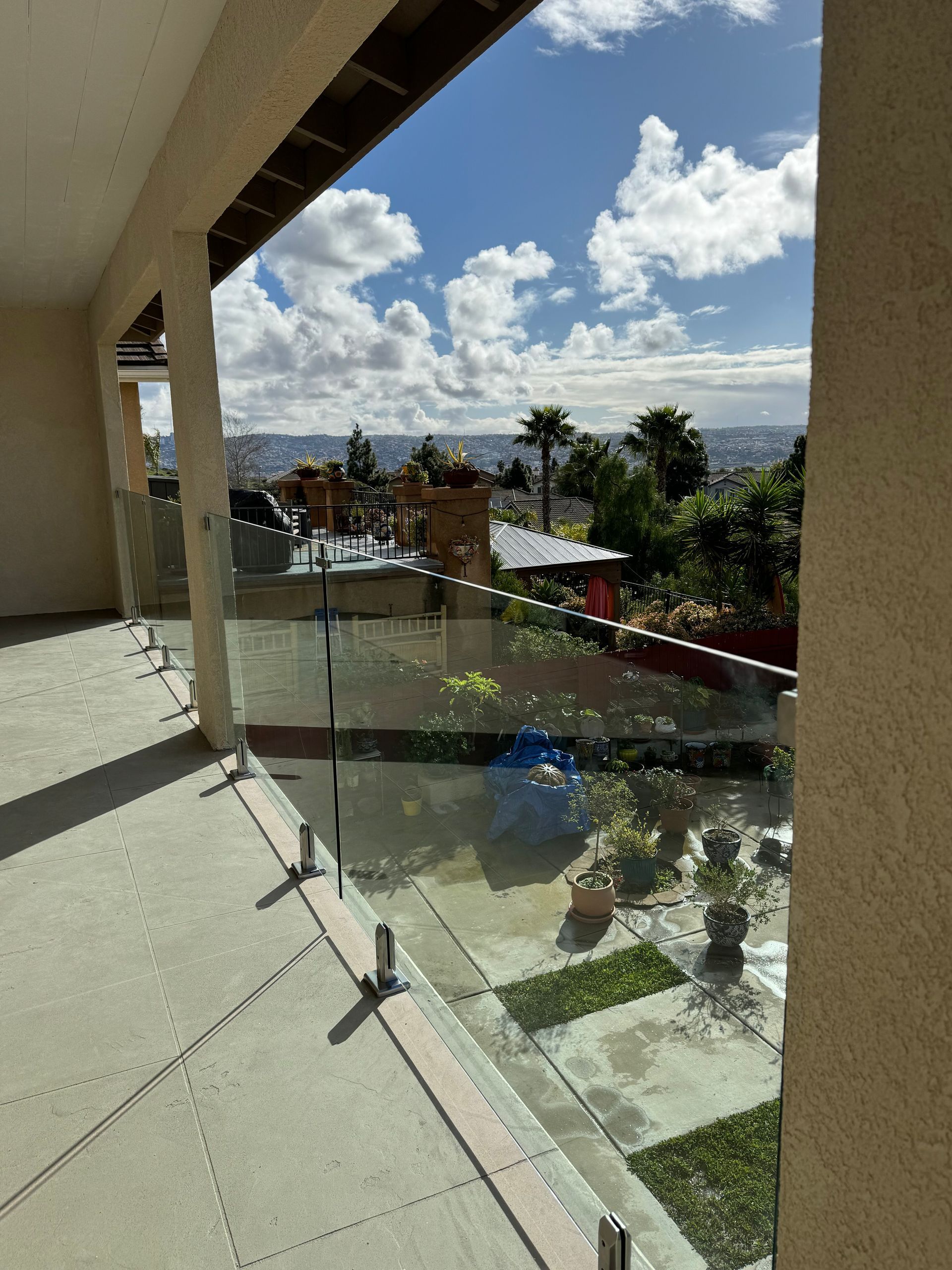 A balcony with a glass railing and a view of a city.