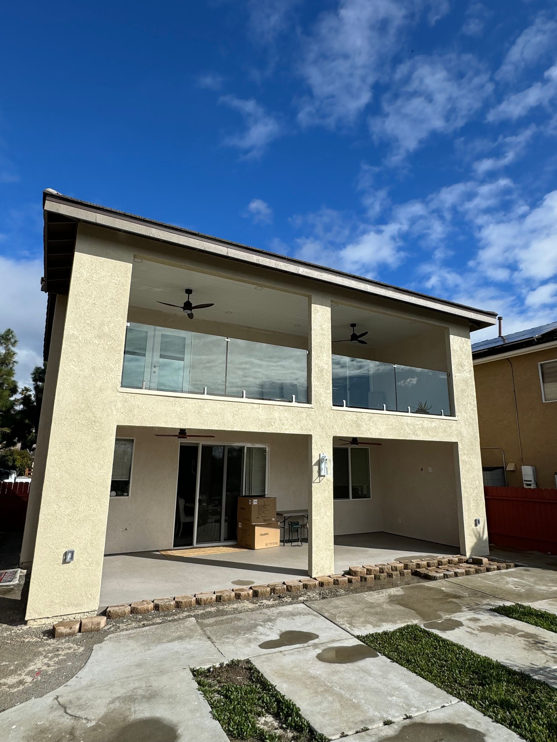 A large white house with a balcony and a blue sky in the background.