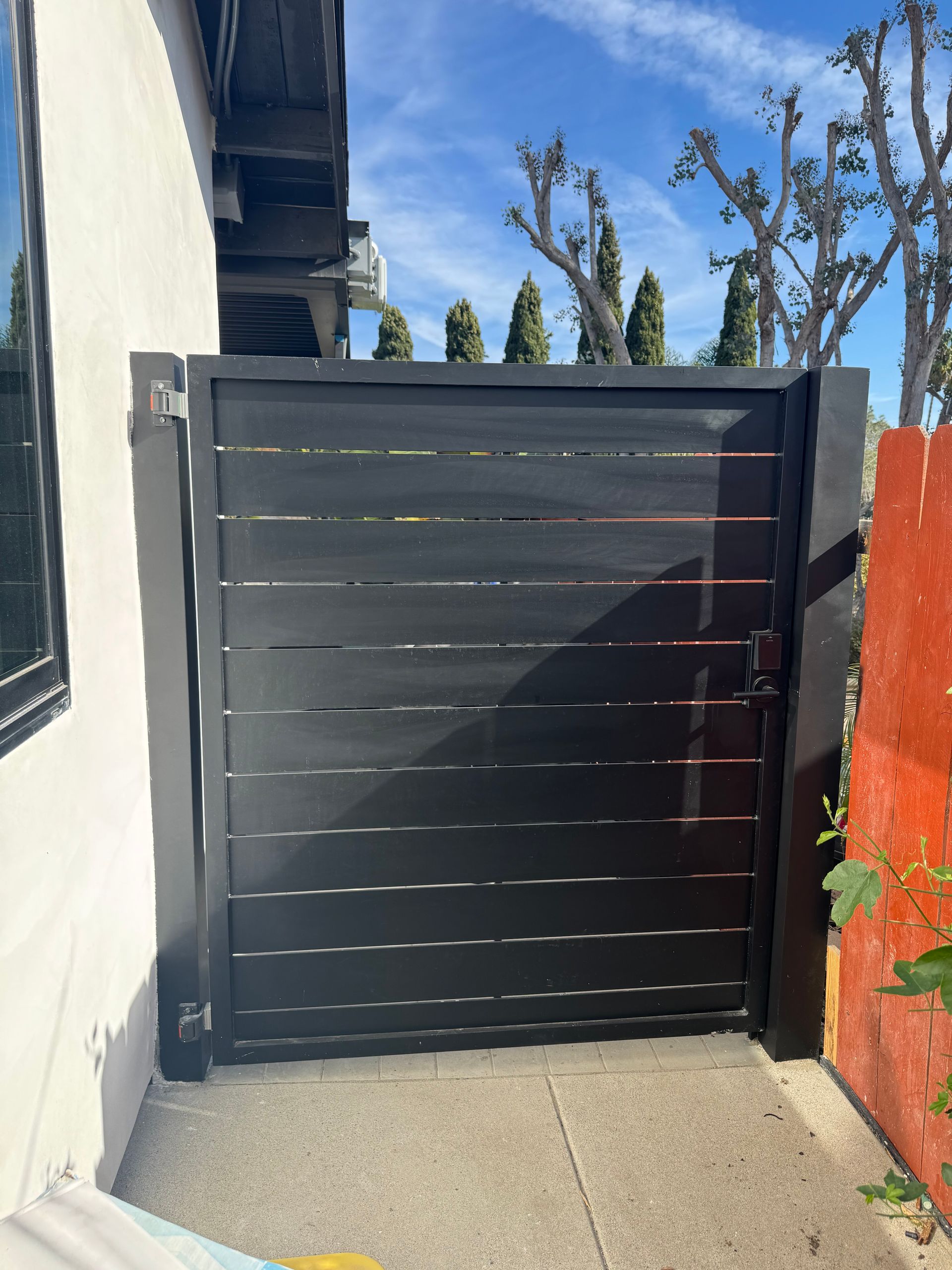 A black gate is sitting in front of a white building.