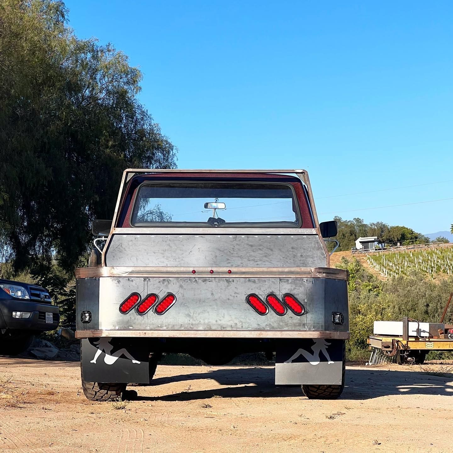 A truck with red lights on the back is parked in a dirt field