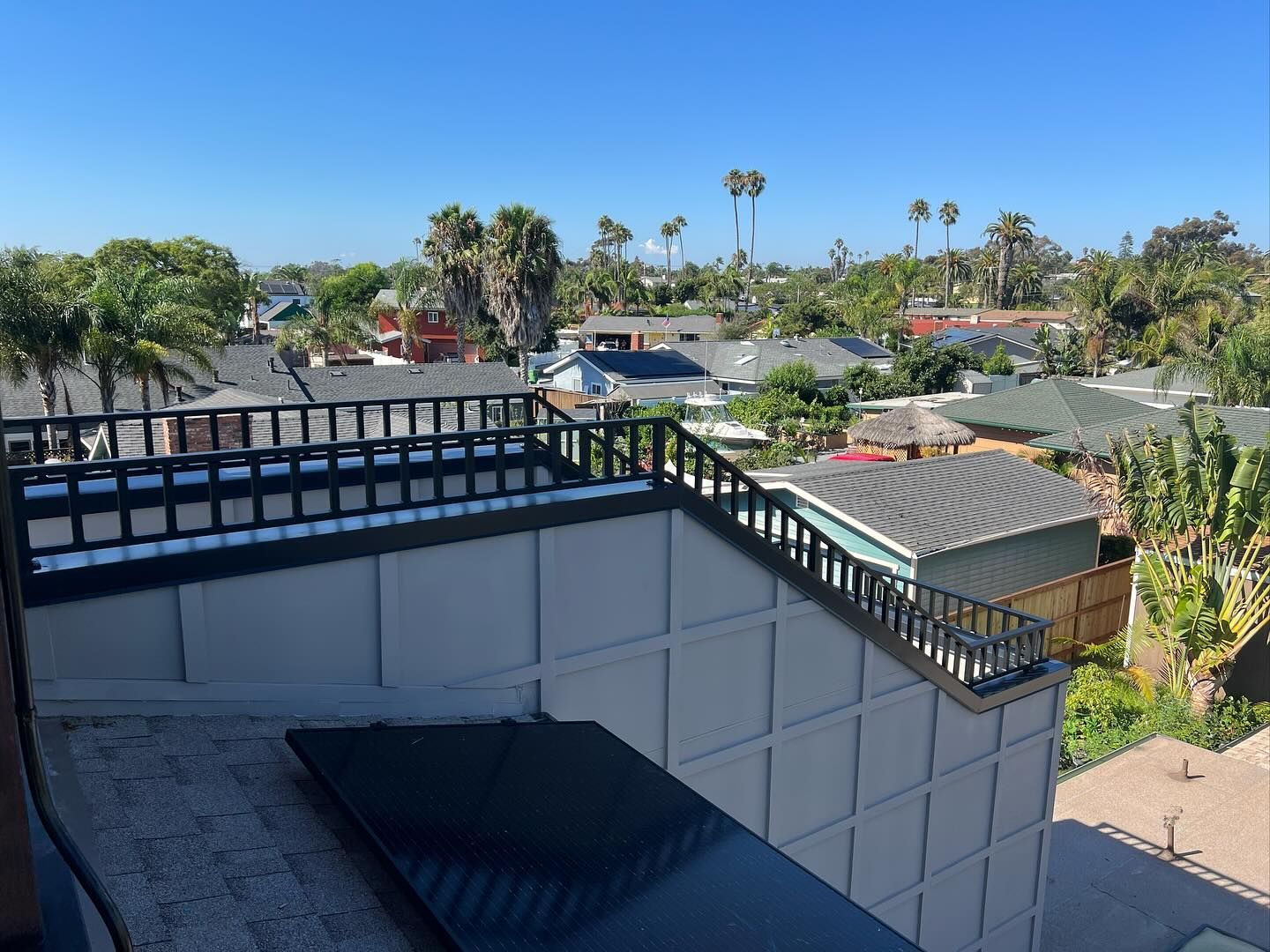 A balcony with a view of a residential area with palm trees