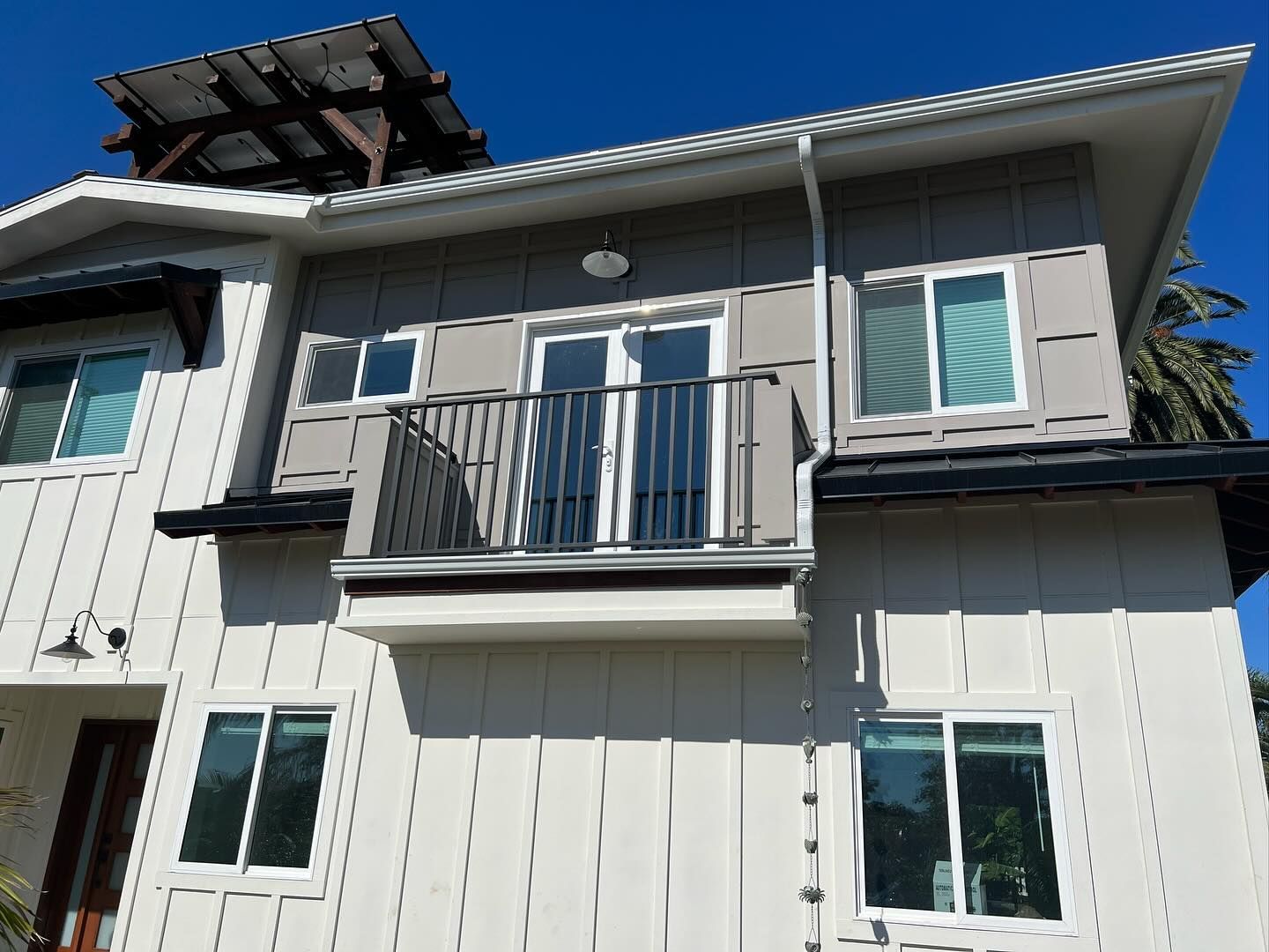 A white house with a balcony and a solar panel on the roof