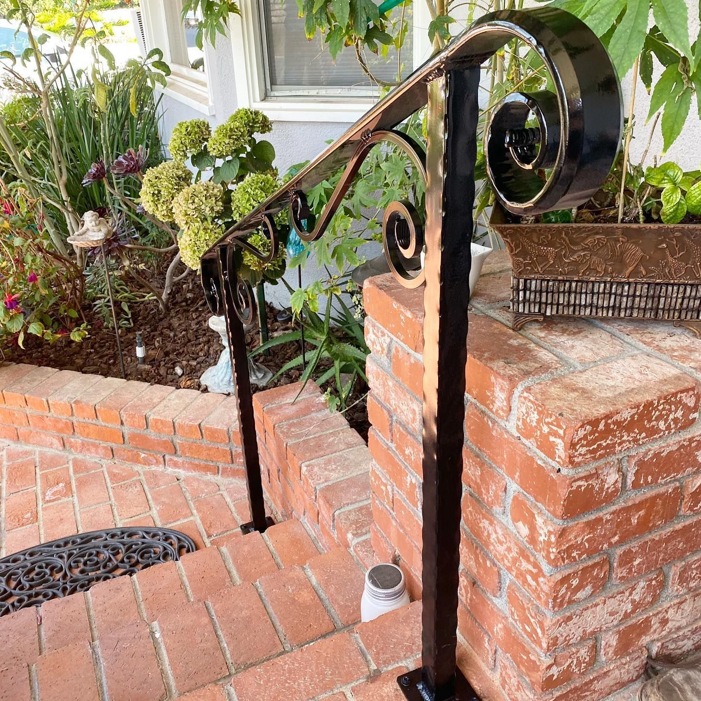 A wrought iron railing is sitting on a brick wall.