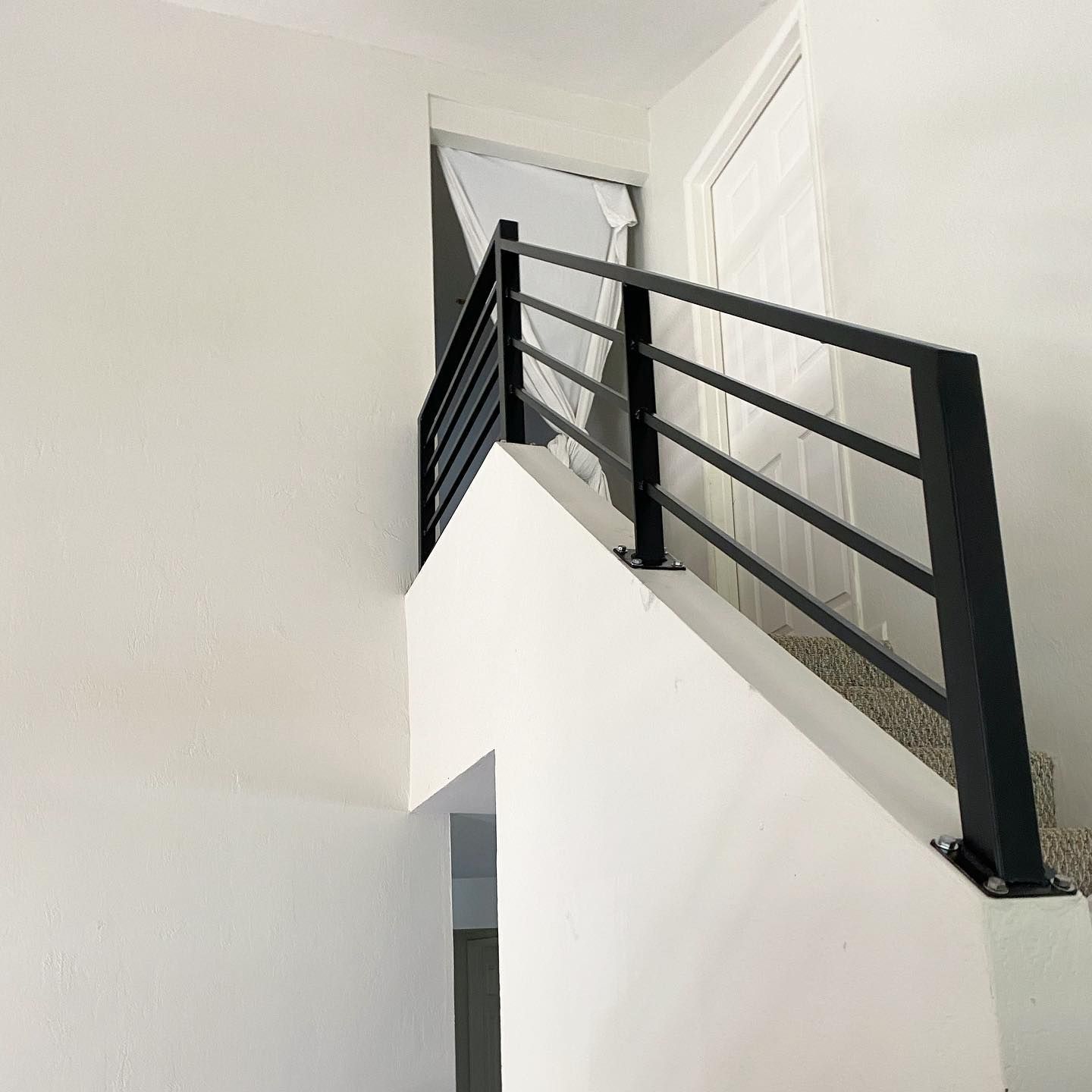 A staircase with a black railing and white walls