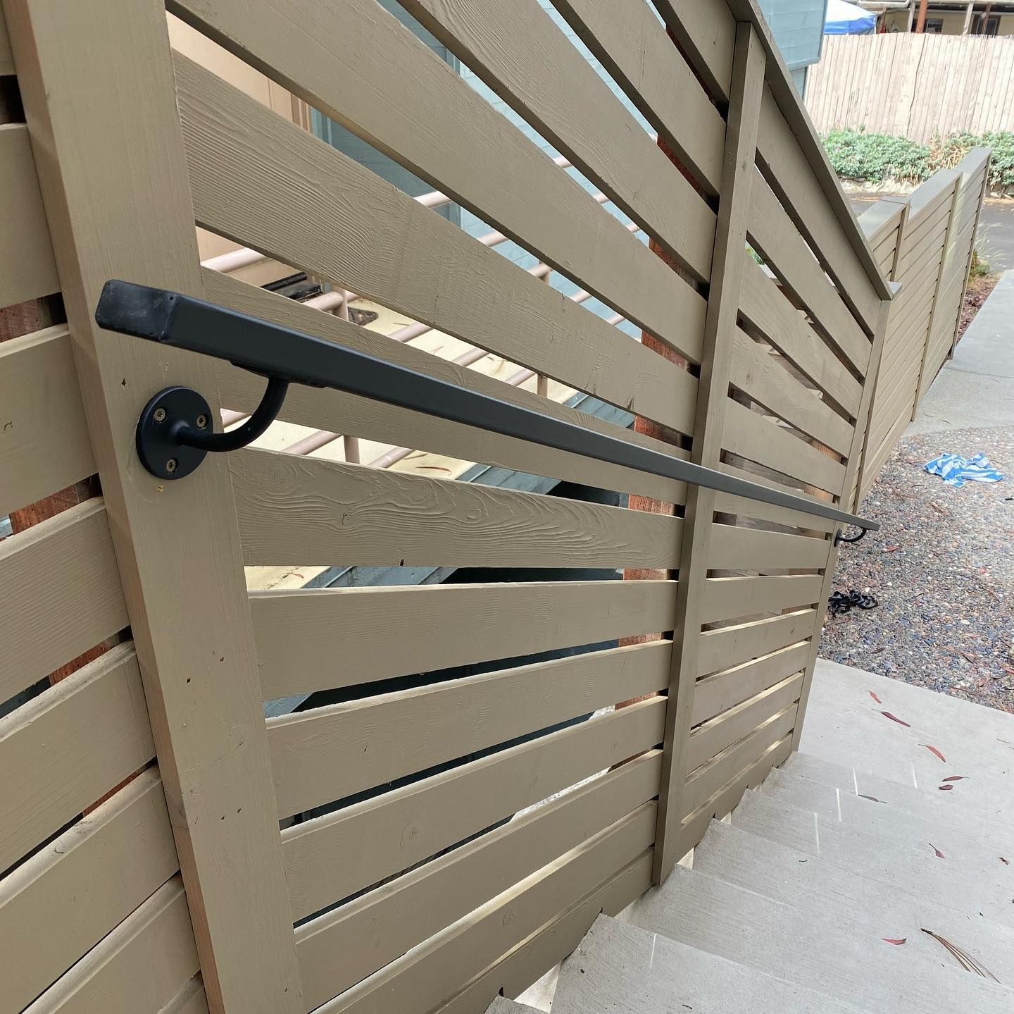 A wooden fence with a black railing is surrounding a set of stairs.