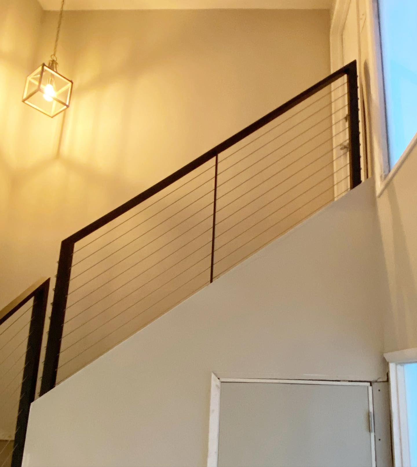 A staircase with a black railing and a light hanging from the ceiling