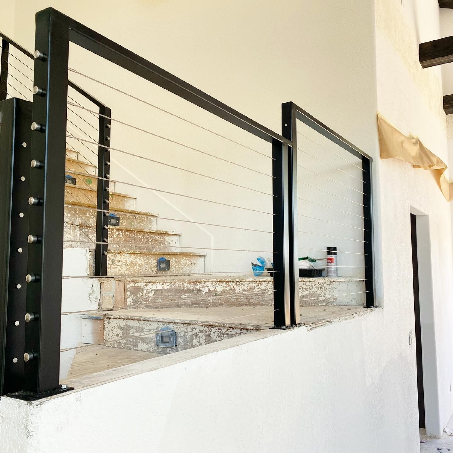 A staircase with a black railing and a white wall