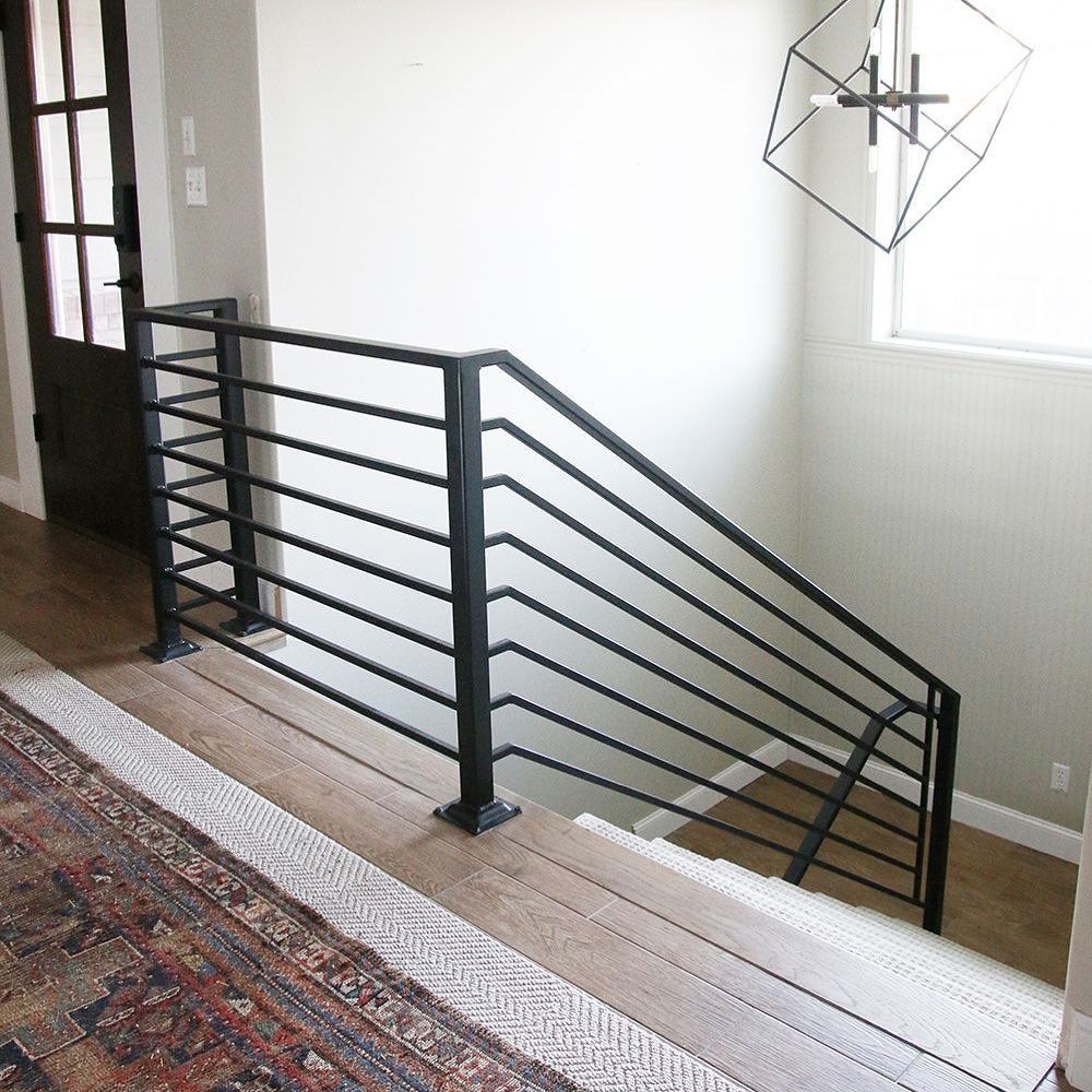 A staircase with a black railing and a rug on the floor.