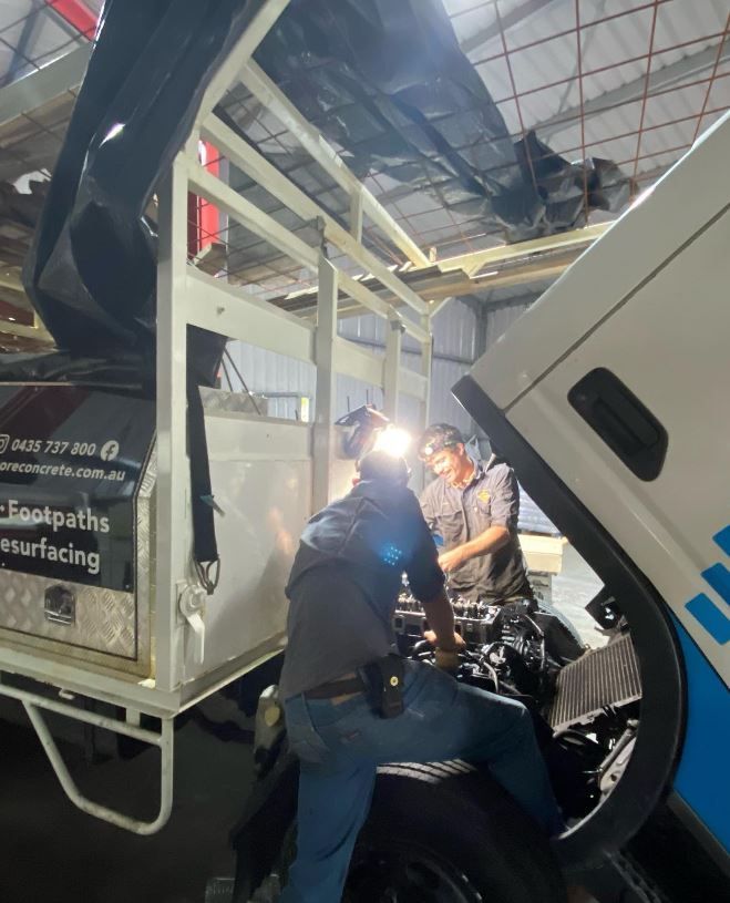 A man is working on the engine of a truck in a garage