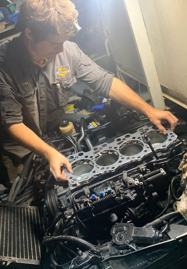 A man is working on a car engine in a garage.
