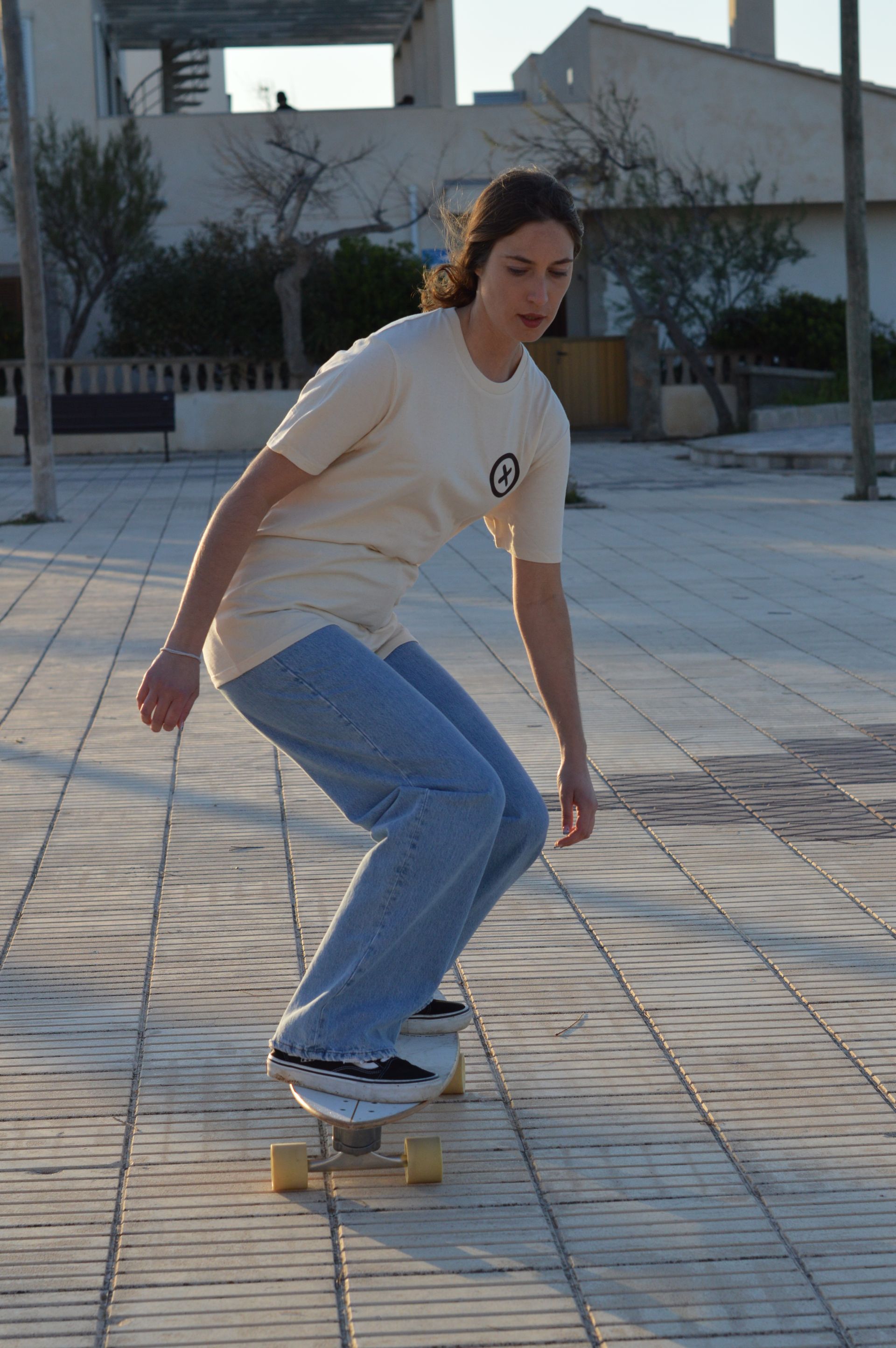 Una mujer anda en skate sobre una acera de ladrillos.