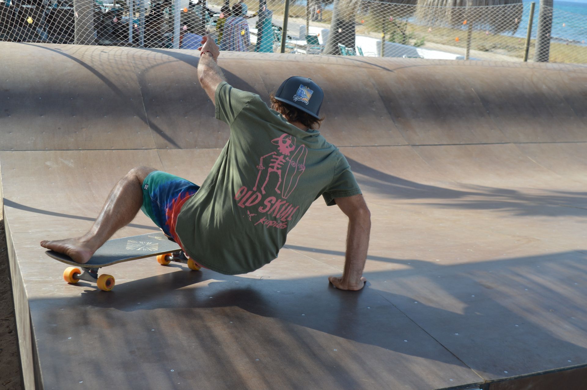 Un hombre con una camisa verde baja una rampa en patineta.