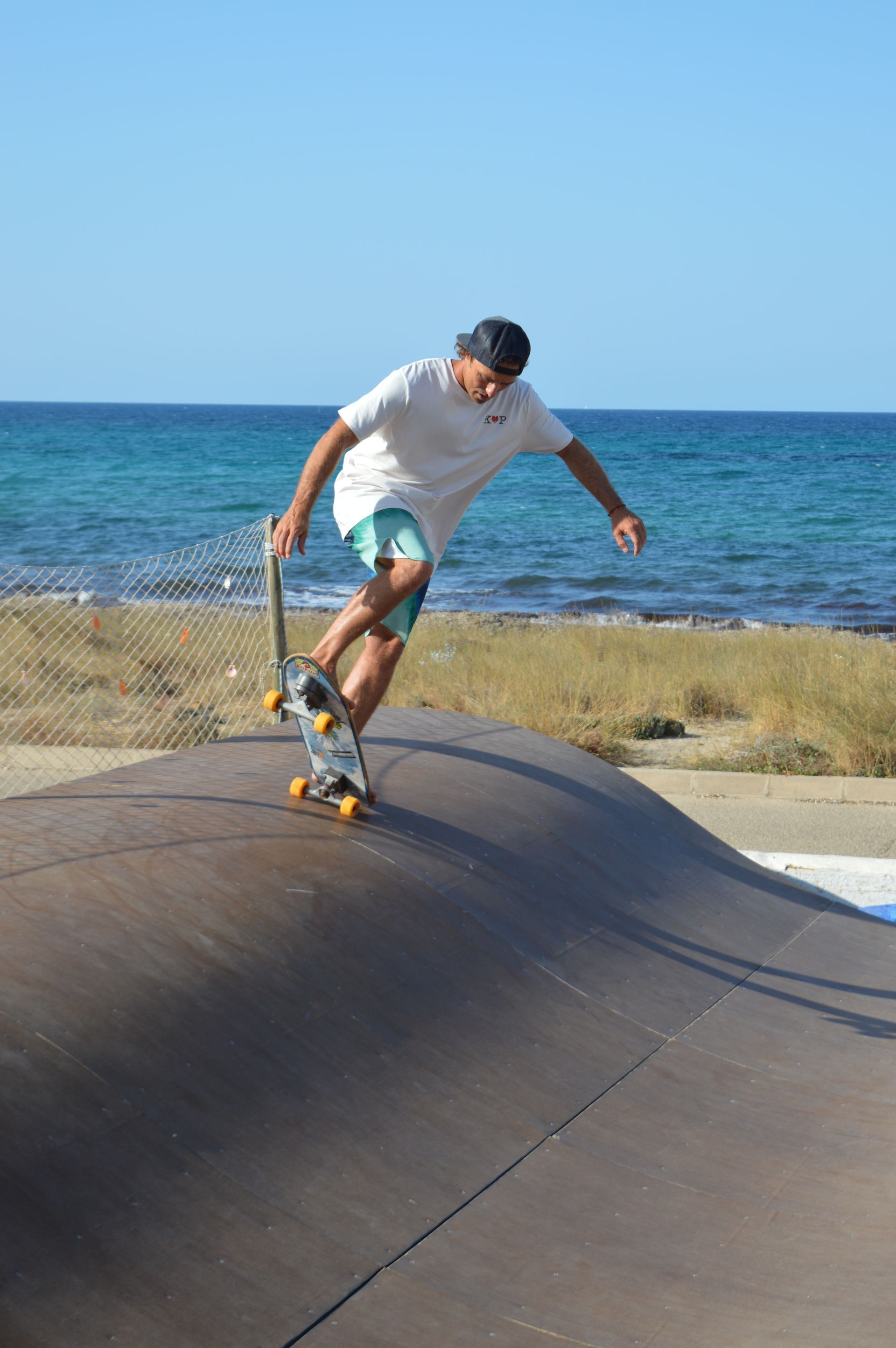 Un hombre está montando una patineta en una rampa cerca del océano.