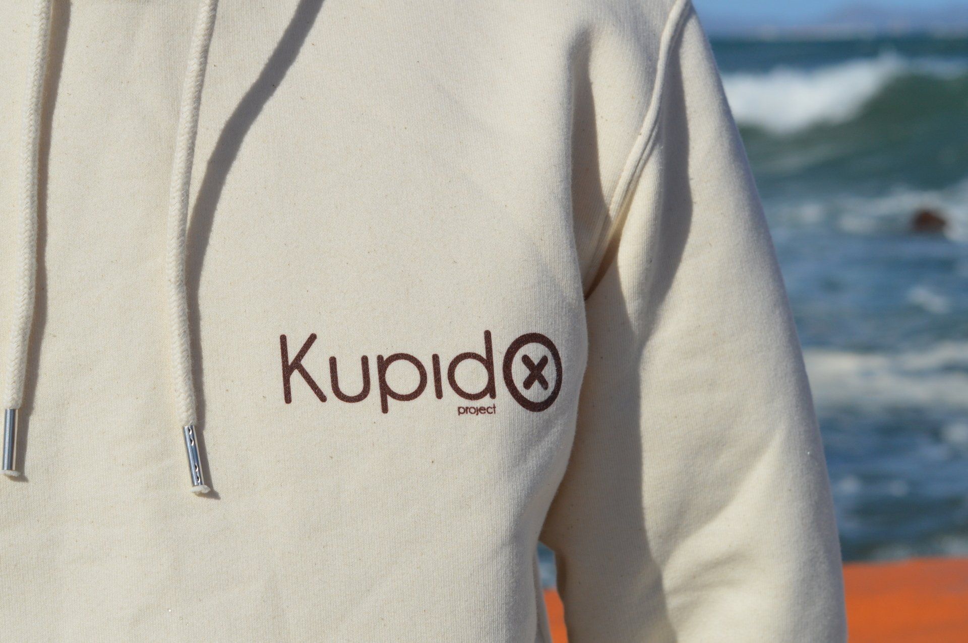 Una persona que lleva una sudadera con capucha blanca con la palabra kupido escrita.