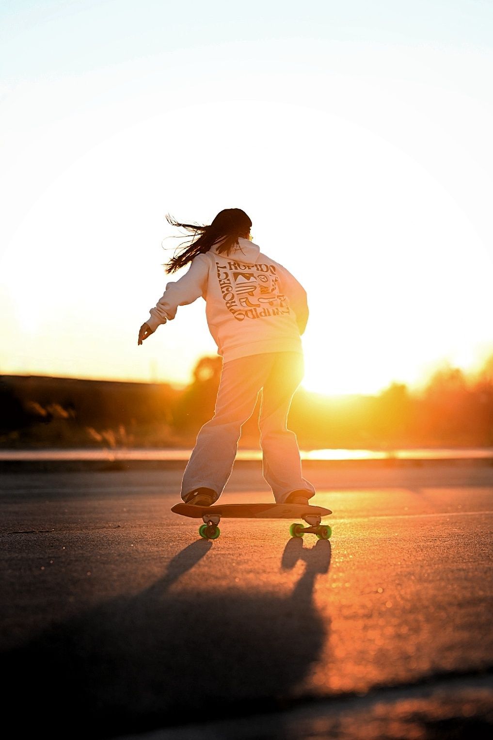 Una mujer anda en patineta por una carretera al atardecer.