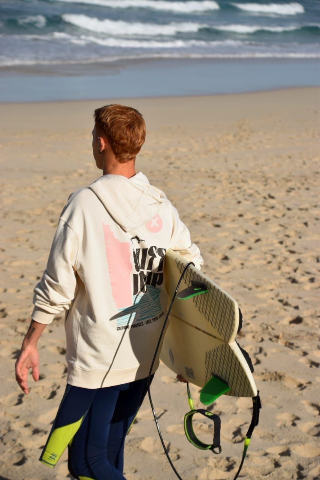 Un hombre lleva una tabla de surf en la playa.