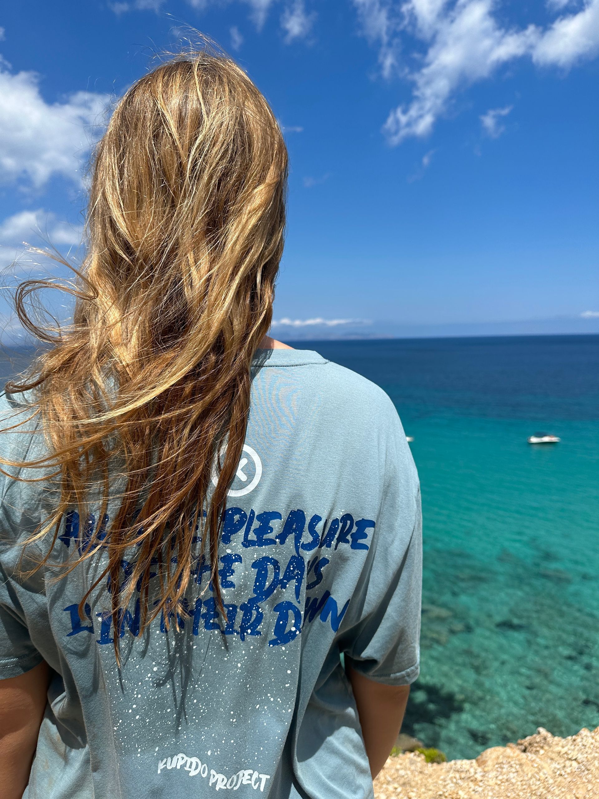 Una mujer está parada en un acantilado con vistas al océano.