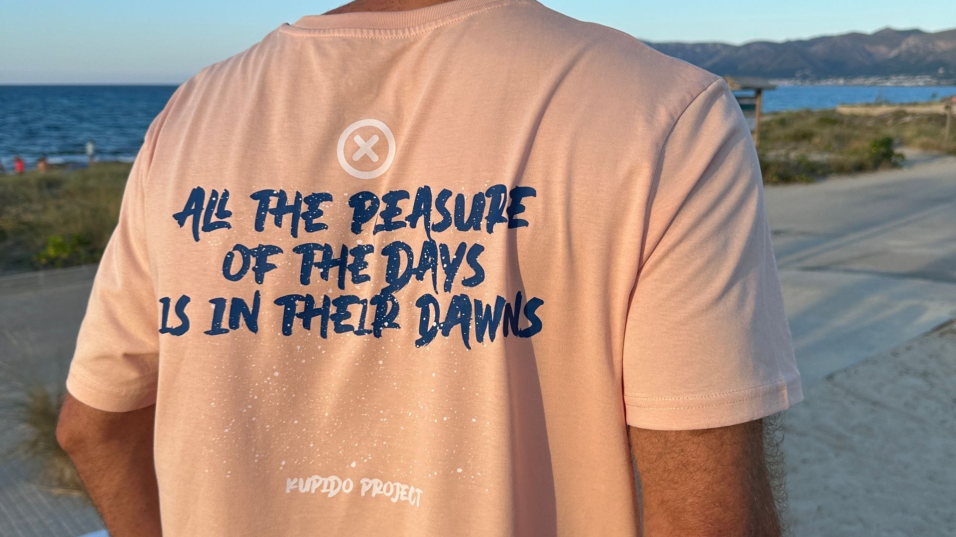 Un hombre con camiseta que dice que todo el placer de los días está en sus amaneceres.