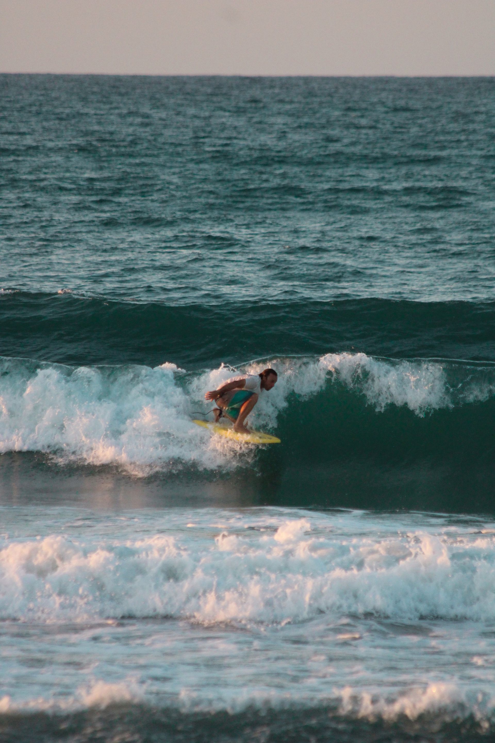 Un hombre monta una ola sobre una tabla de surf en el océano.