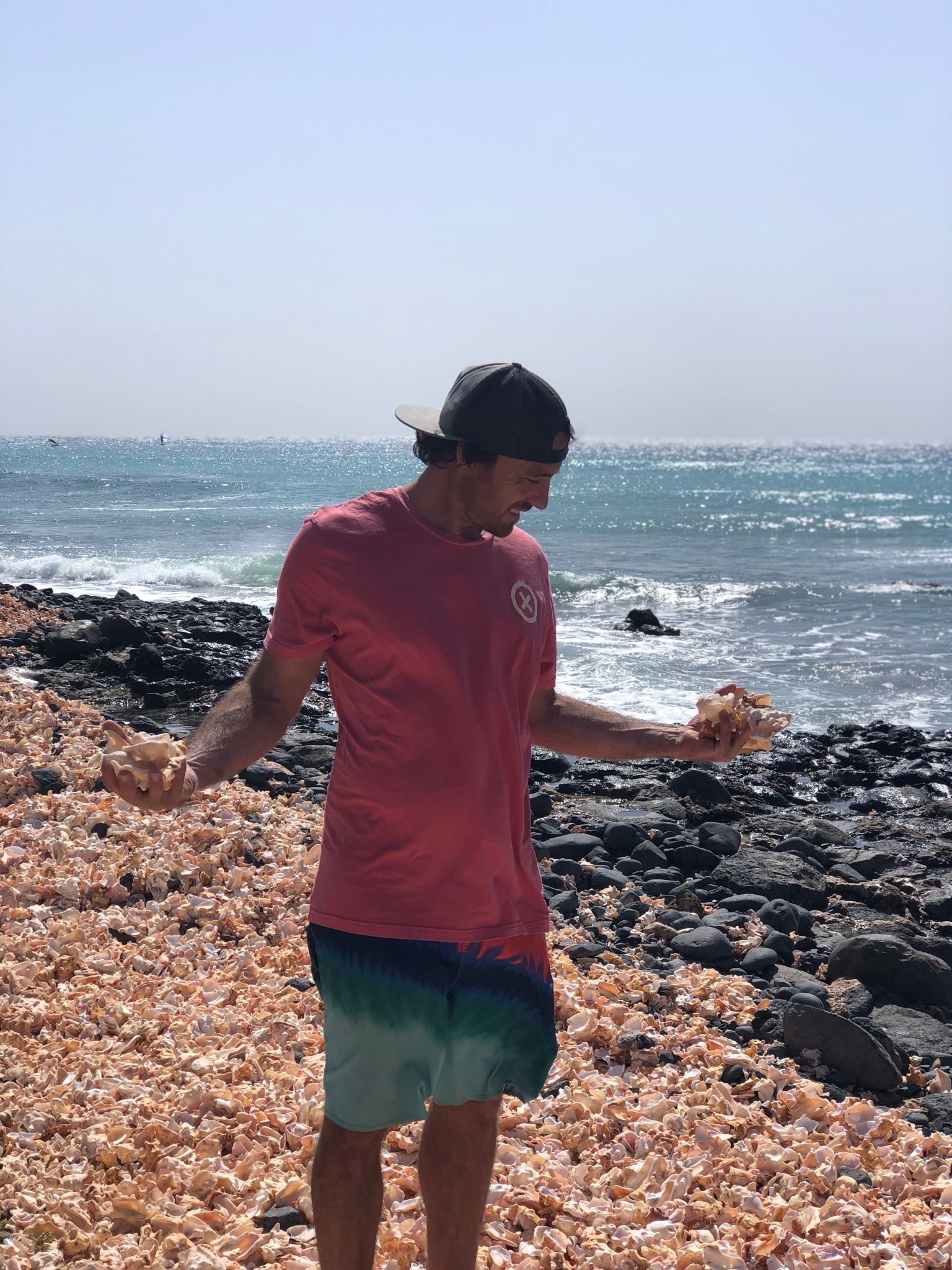 Un hombre está parado en una playa rocosa cerca del océano.