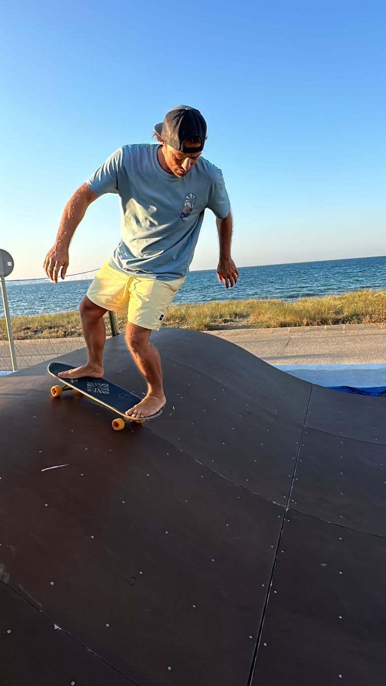 Un hombre anda en patineta por una rampa cerca del océano.