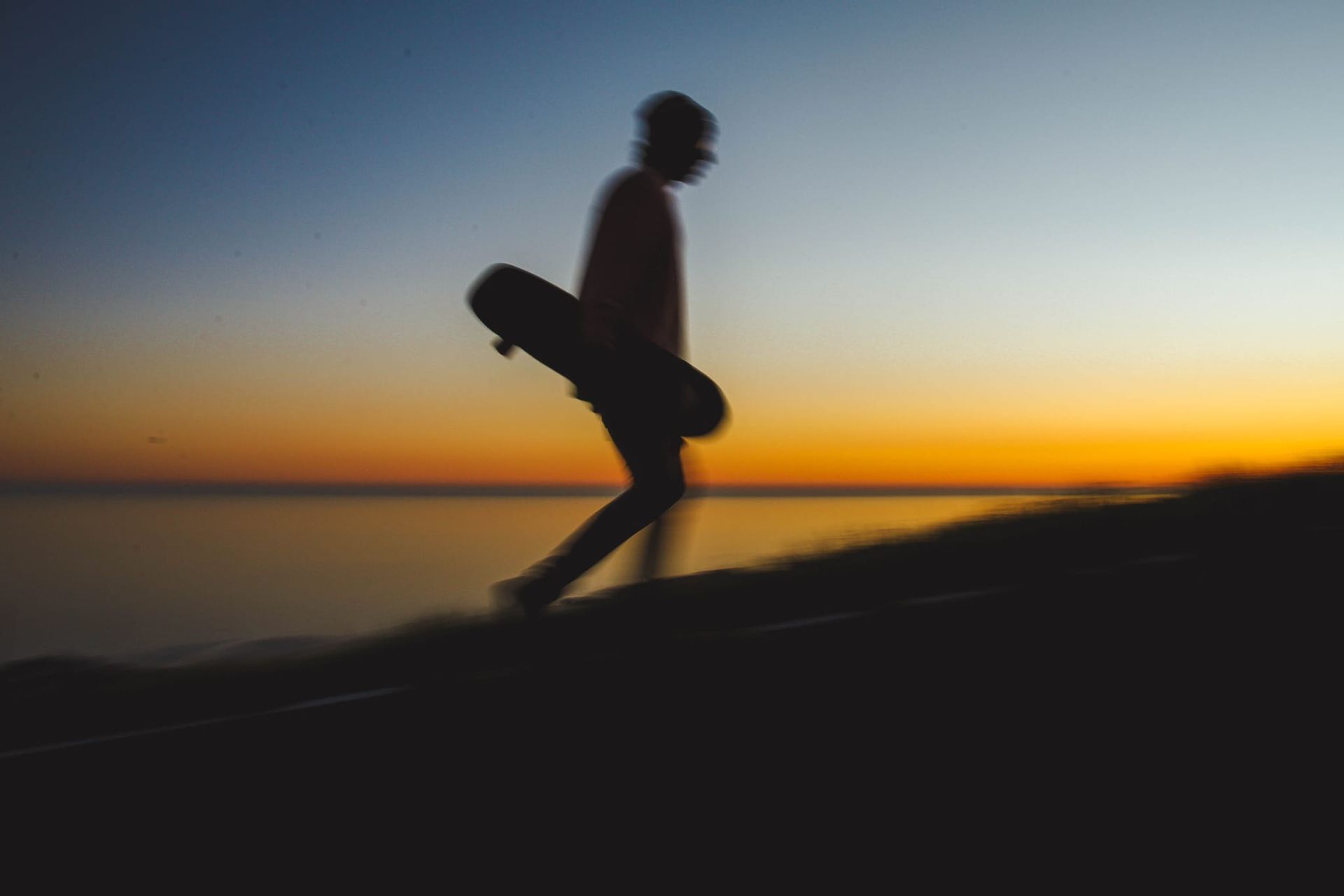 Un hombre camina con una patineta en la mano.