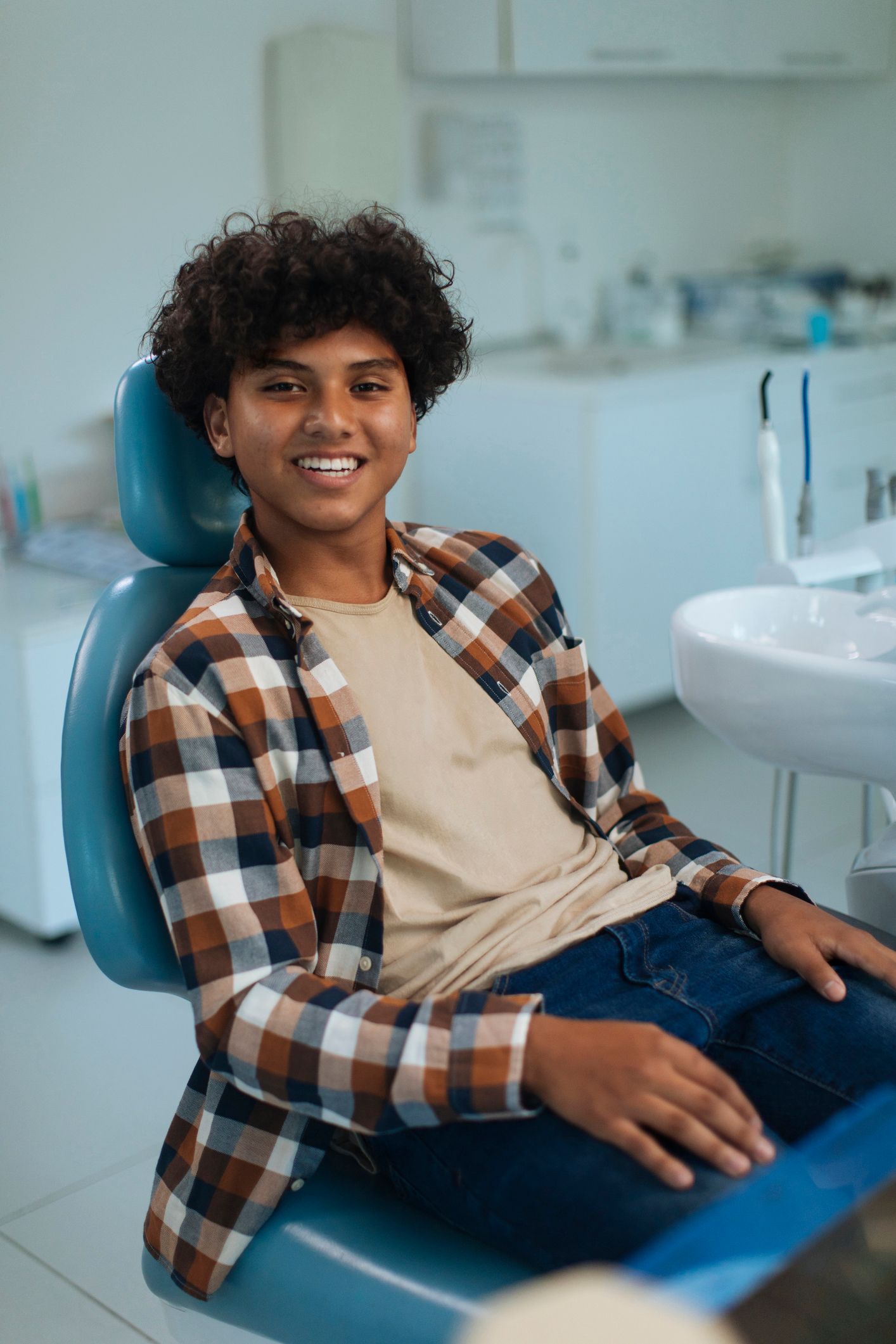 A young man is sitting in a dental chair and smiling.