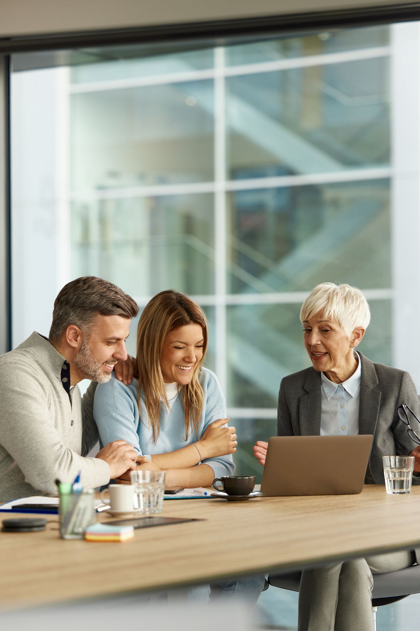 A man and a woman are sitting at a table looking at a laptop.