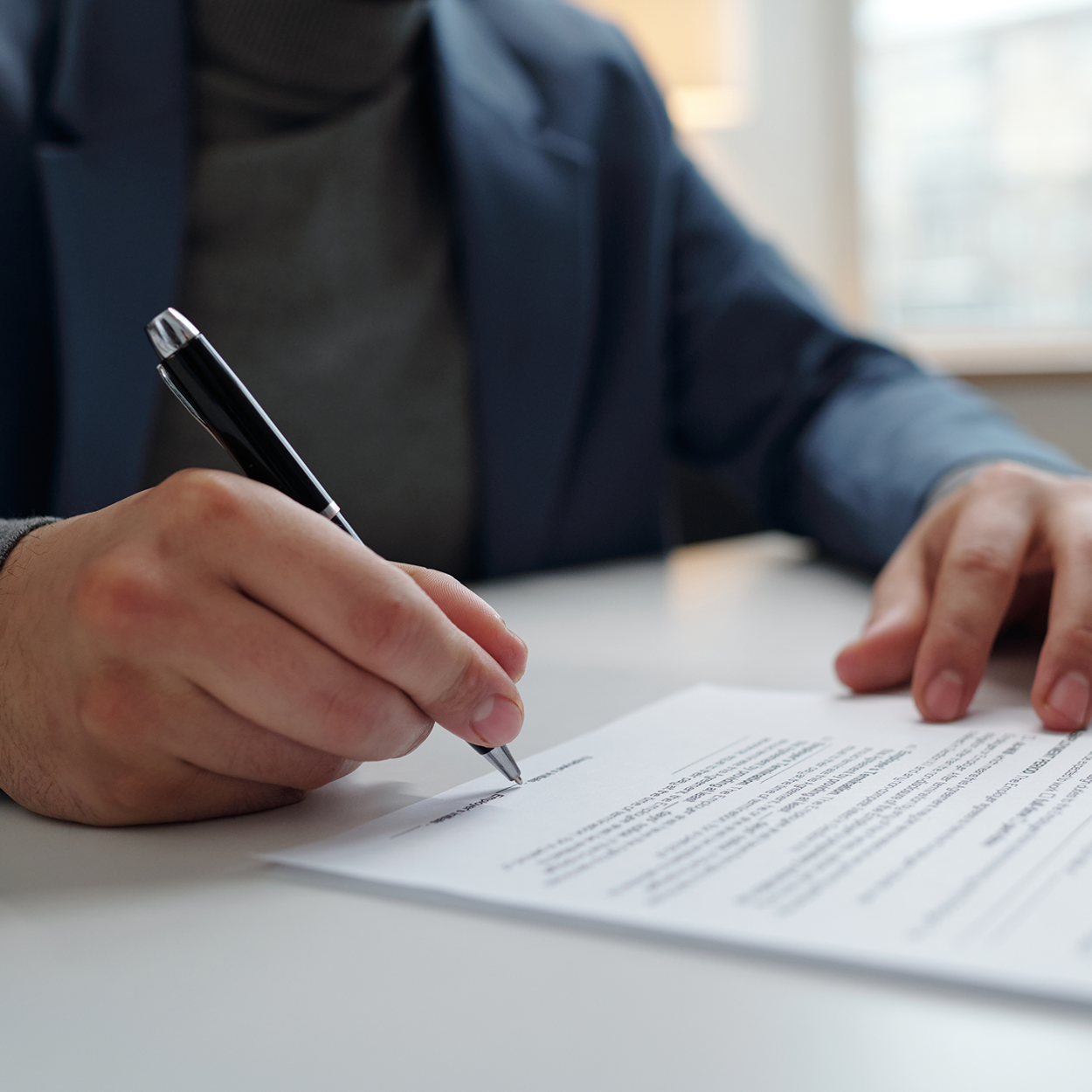 A person is writing on a piece of paper with a pen