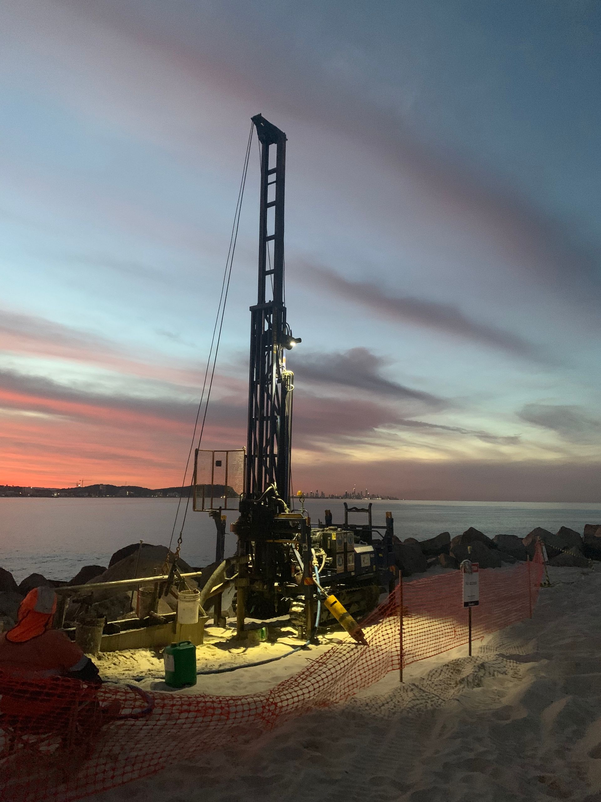 A Large Machine is parked by water with sunset in background — North Coast Drilling & Wicks in Bangalow, NSW