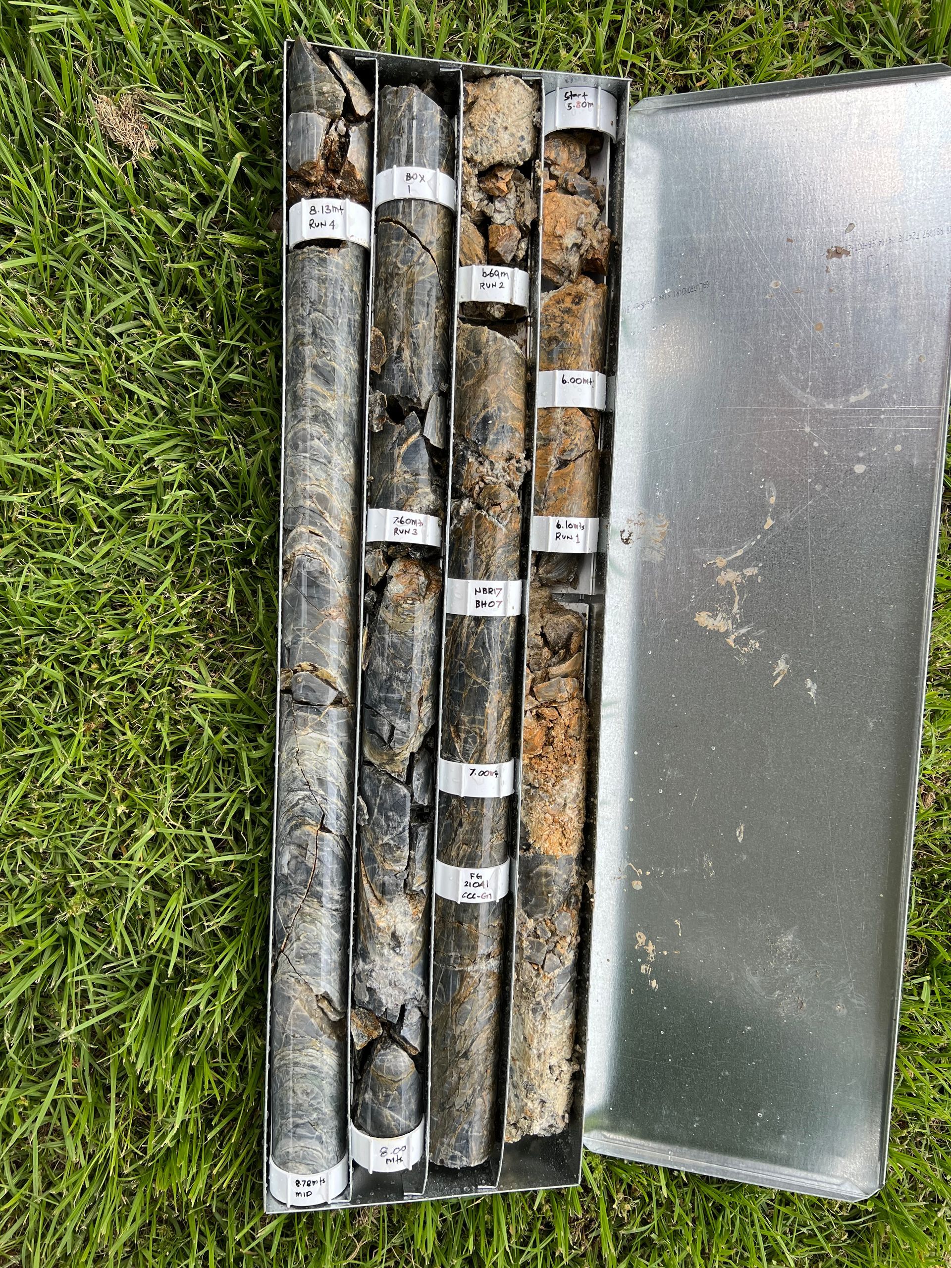 Four clear pipes are laying on grass while filled with rock — North Coast Drilling & Wicks in Bangalow, NSW