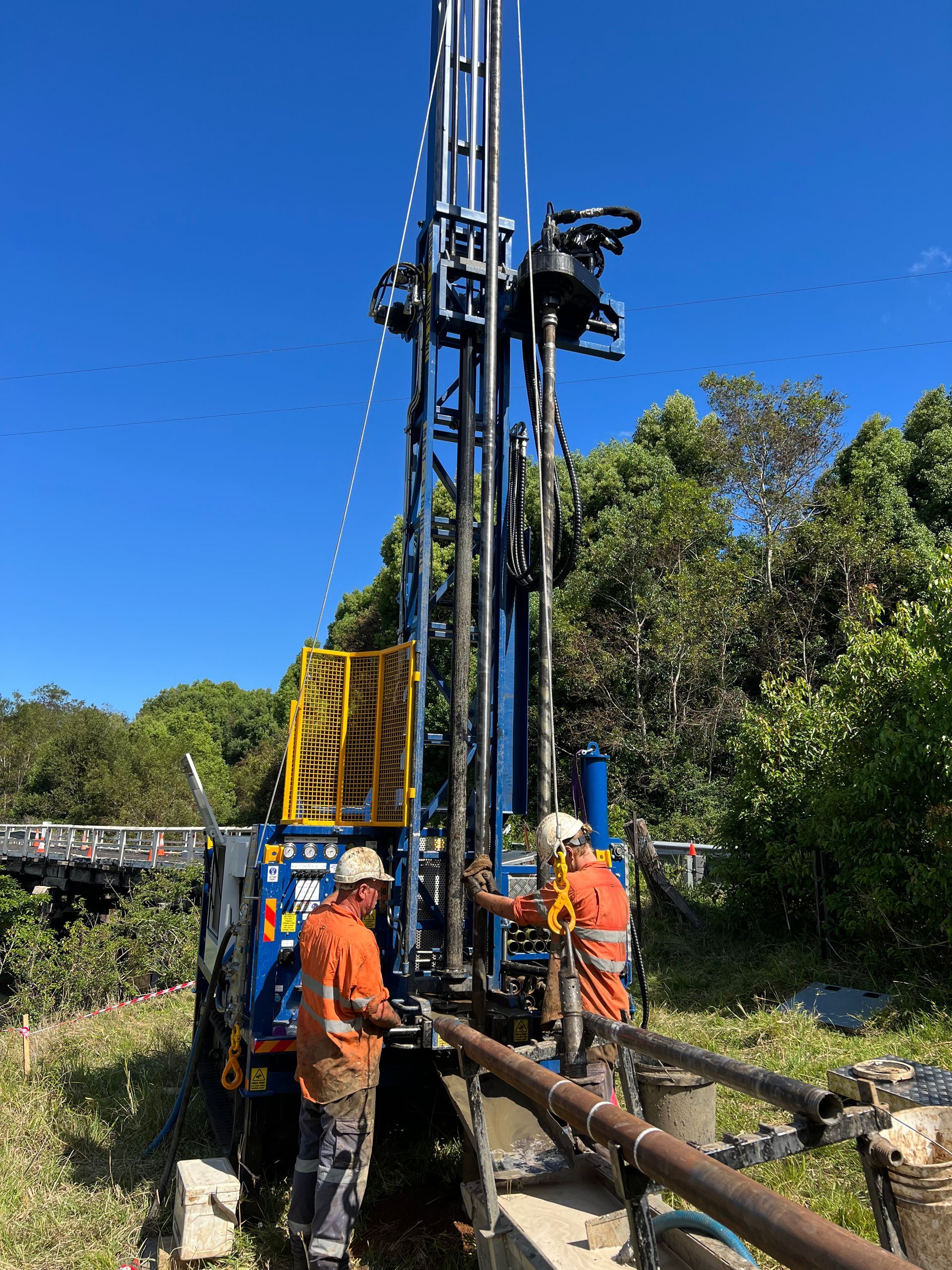 Two workers are holding a machine while surrounded by bush — North Coast Drilling & Wicks in Bangalow, NSW