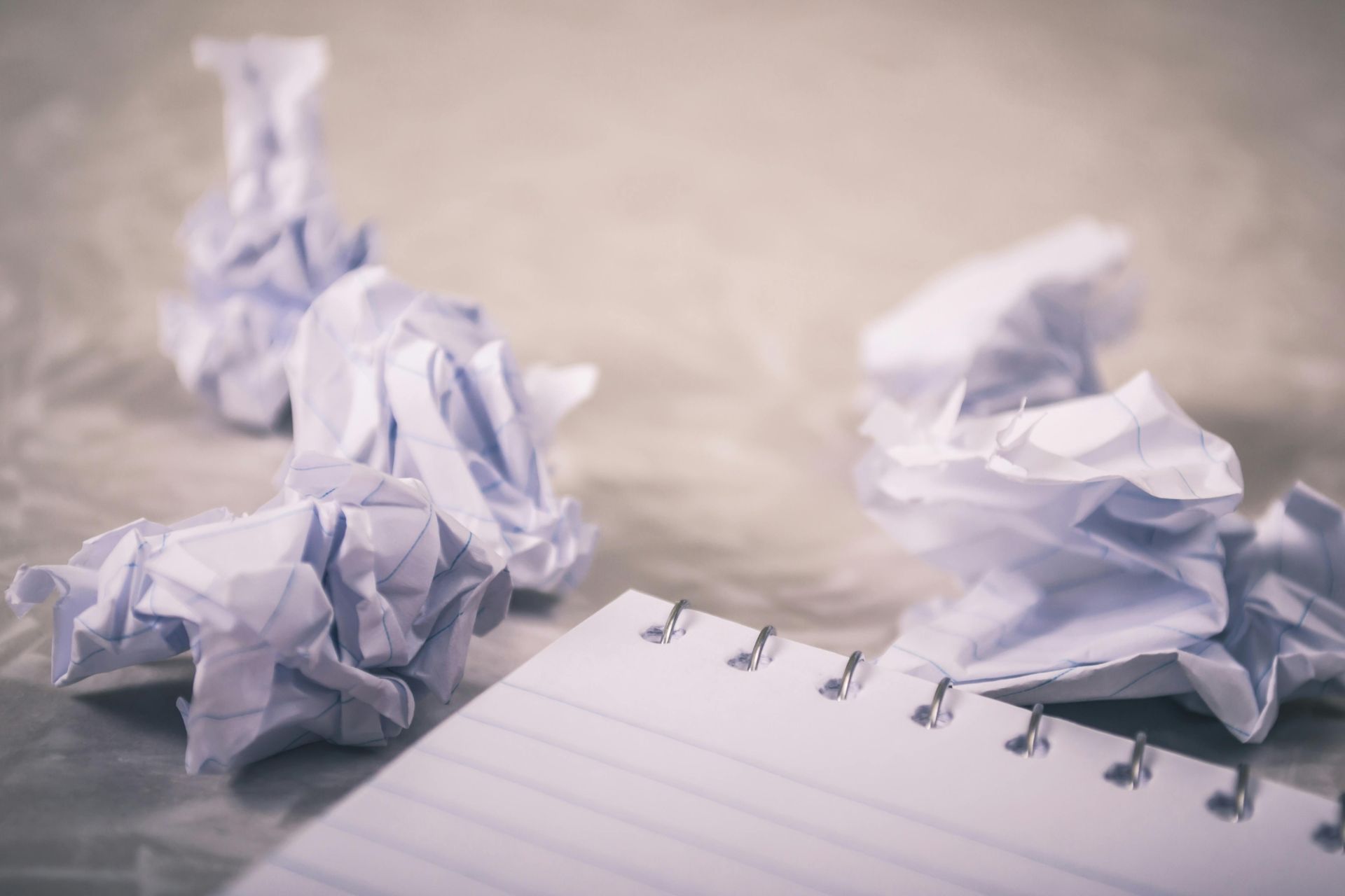 White crumpled paper balls and a notebook on a light surface.