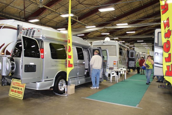 A group of people are looking at a rv in a garage.