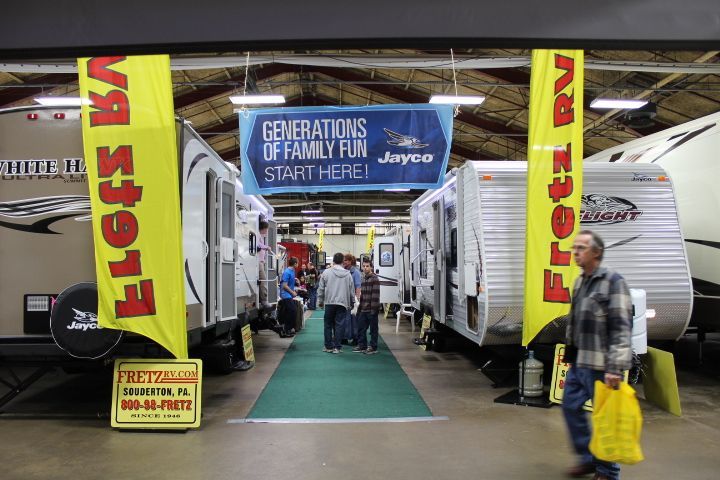 A man is walking through a rv showroom with a sign that says `` generations of family fun start here ''.