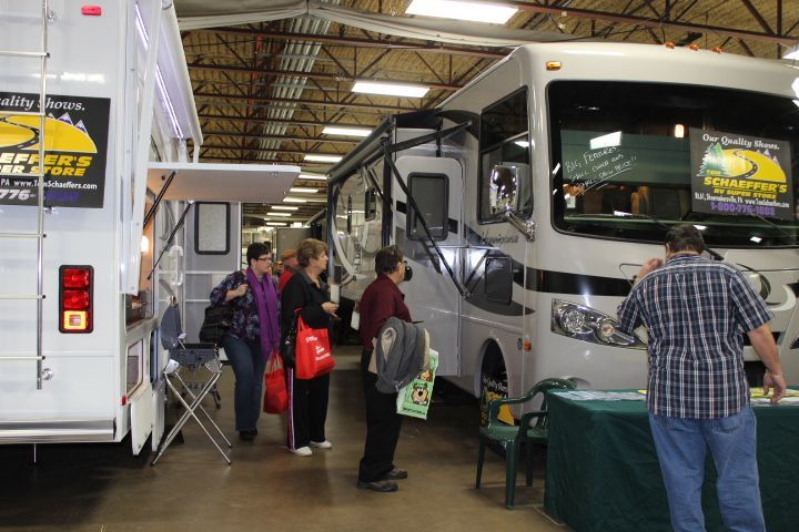 A man in a plaid shirt is standing in front of a rv