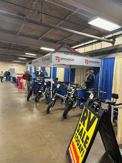 A row of motorcycles are lined up in a room with a sign that says rv sale today.