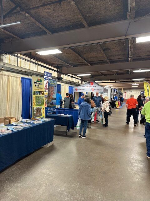 A group of people are standing around tables in a room.