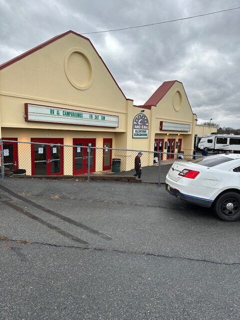 A white car is parked in front of a building that has a sign that says ' r.l. emporium ' on it
