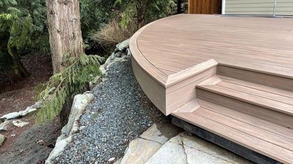 A wooden deck with stairs and a tree in the background.