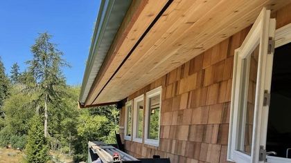 A house with wooden siding and white windows is being built.