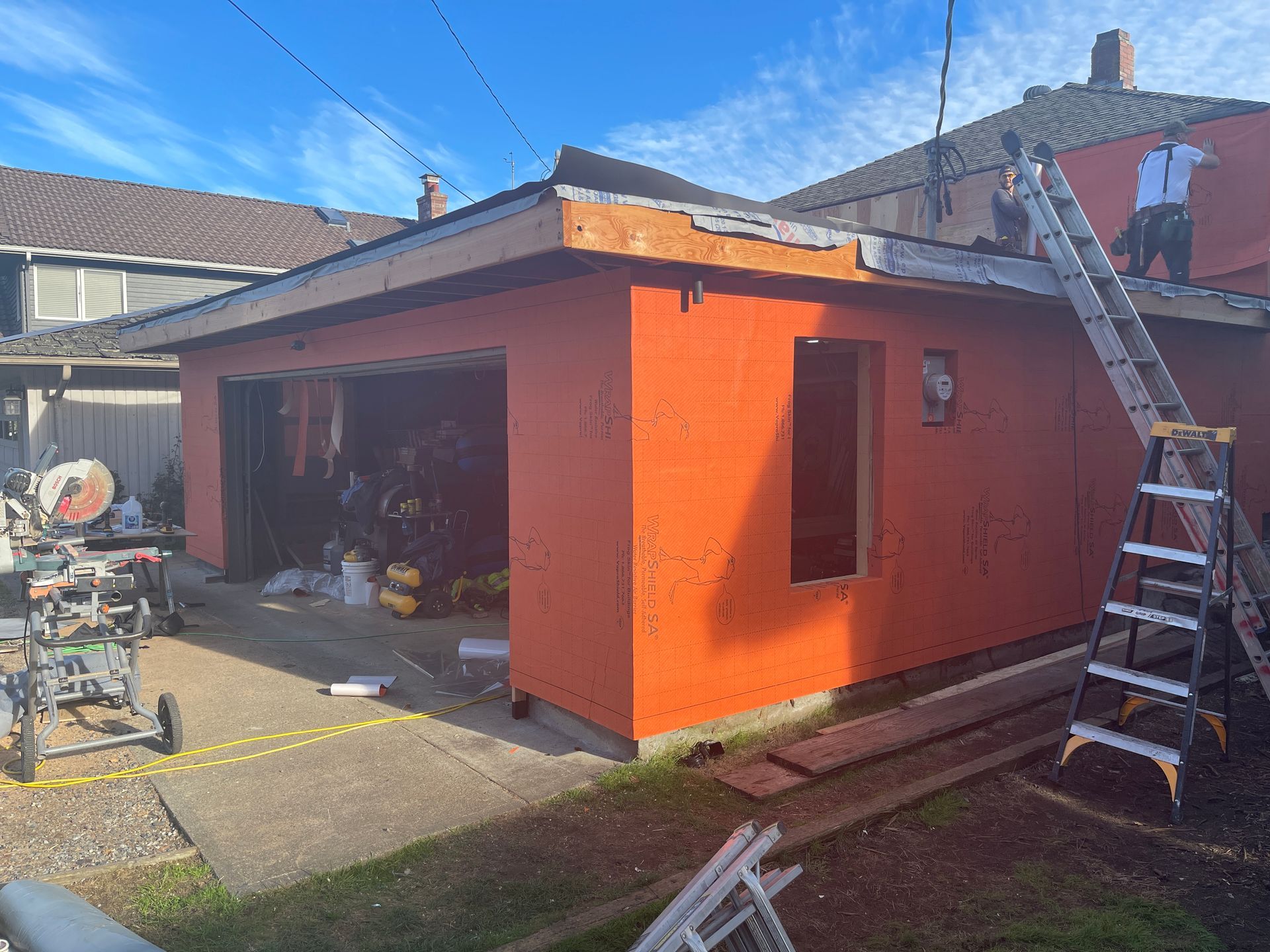 A garage is being remodeled in a backyard with a ladder.