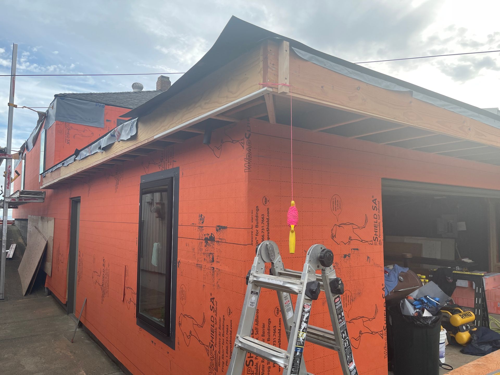 A ladder is sitting on the side of an orange building.