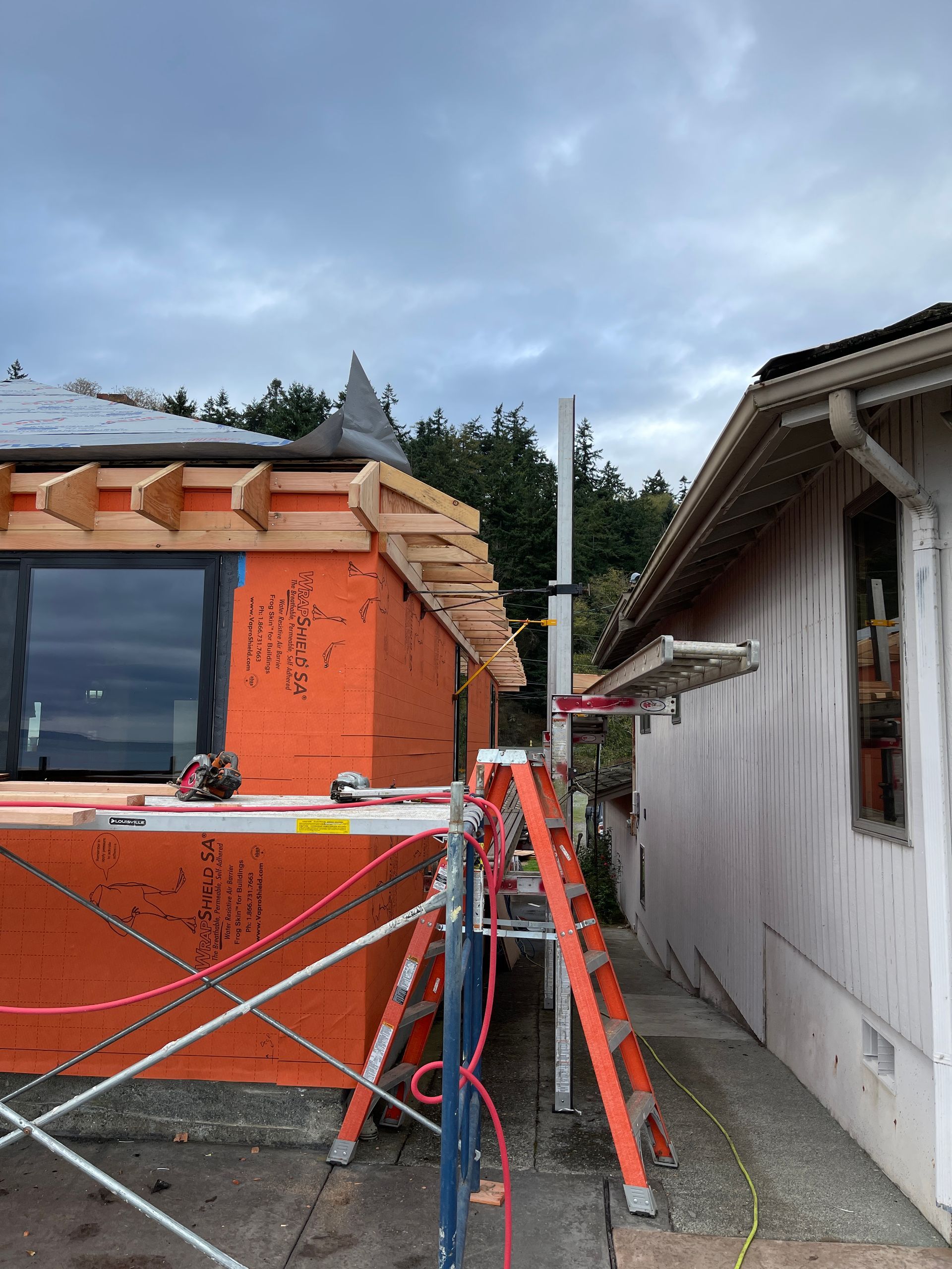 A house is being remodeled and a ladder is sitting in front of it.