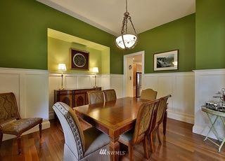 A dining room with a wooden table and chairs and green walls.