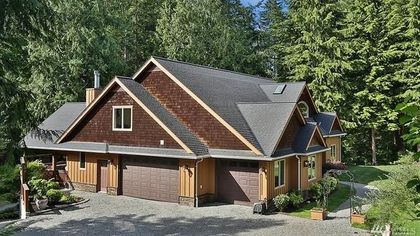 A large house with a garage is surrounded by trees.