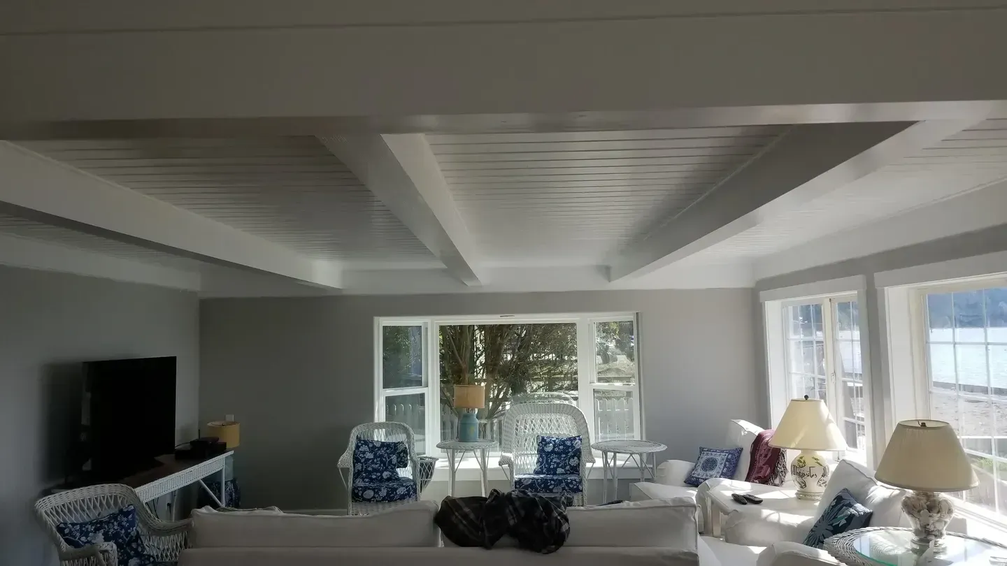 A living room with a couch , chairs , lamps and a television.