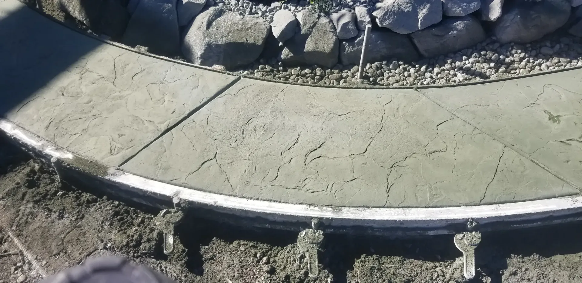 A concrete walkway is being built next to a rock wall